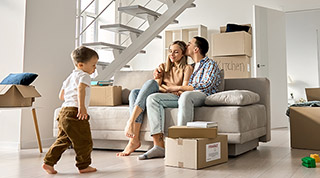 Happy family couple new home owners buyers relaxing on couch with kid child son playing around boxes on moving day in living room. Relocation and house renovation, estate property purchase, removal.; Shutterstock ID 2013487652; purchase_order: -; job: -; client: -; approver: -